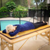 A woman laying on top of a table near the pool.
